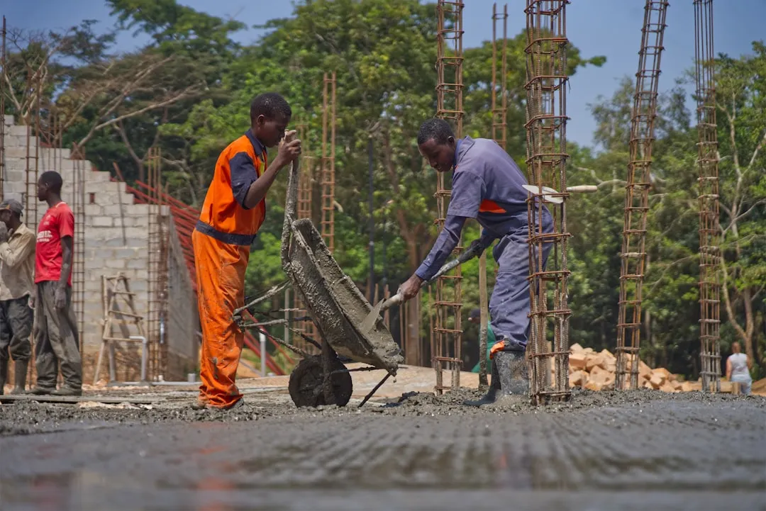 Construction workers pouring concrete with a wheelbarrow.