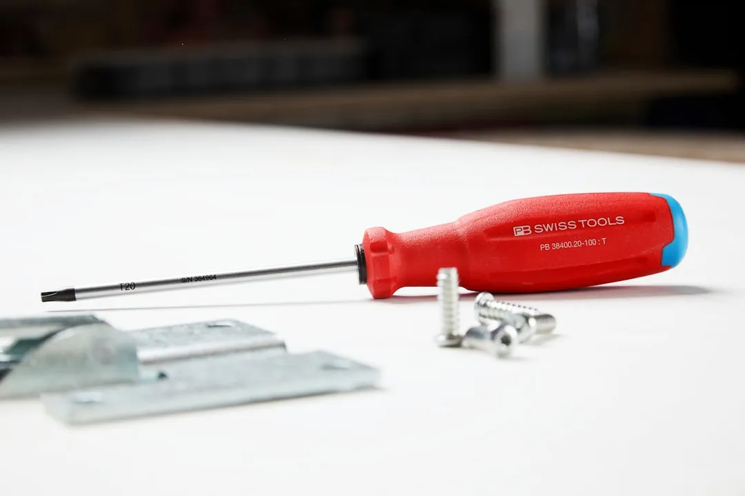 A screwdriver and some hardware are on a surface.