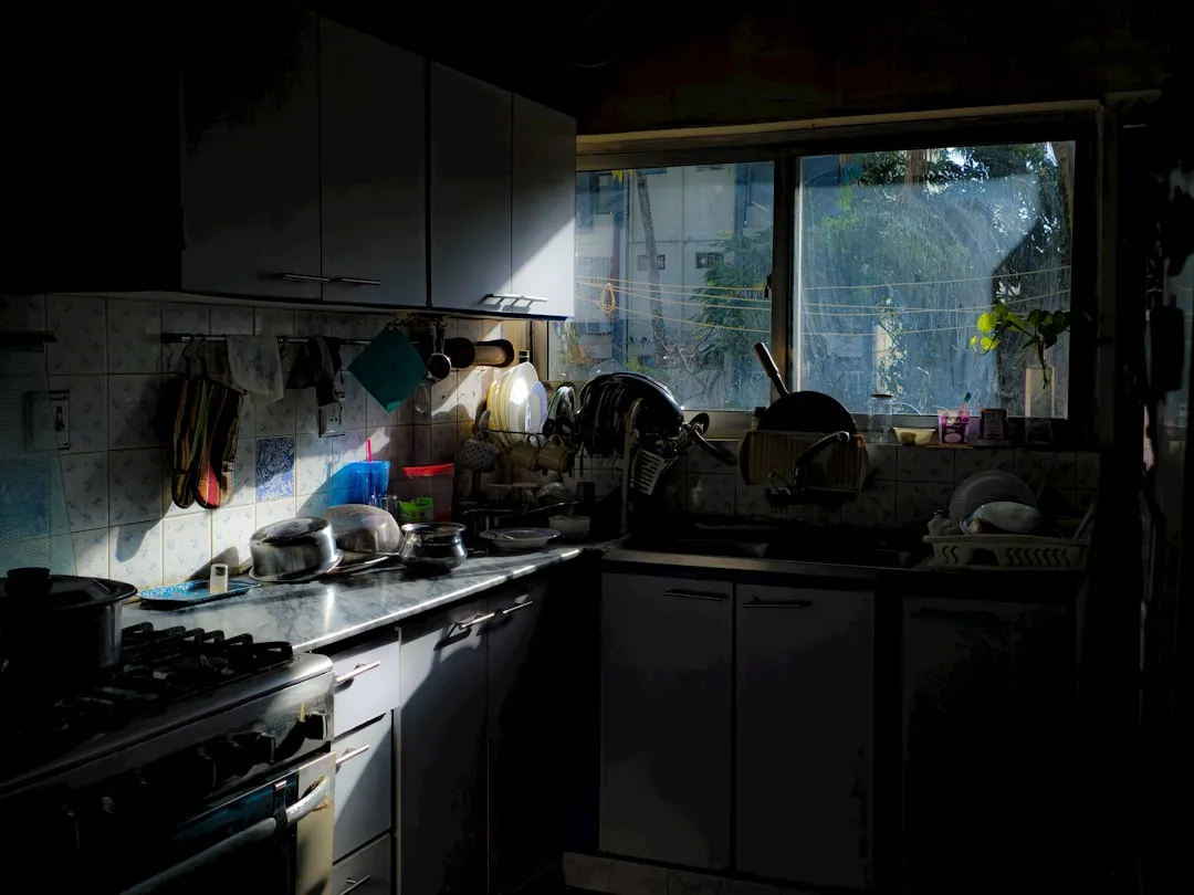 Sunlight streams through a window into a cluttered kitchen.