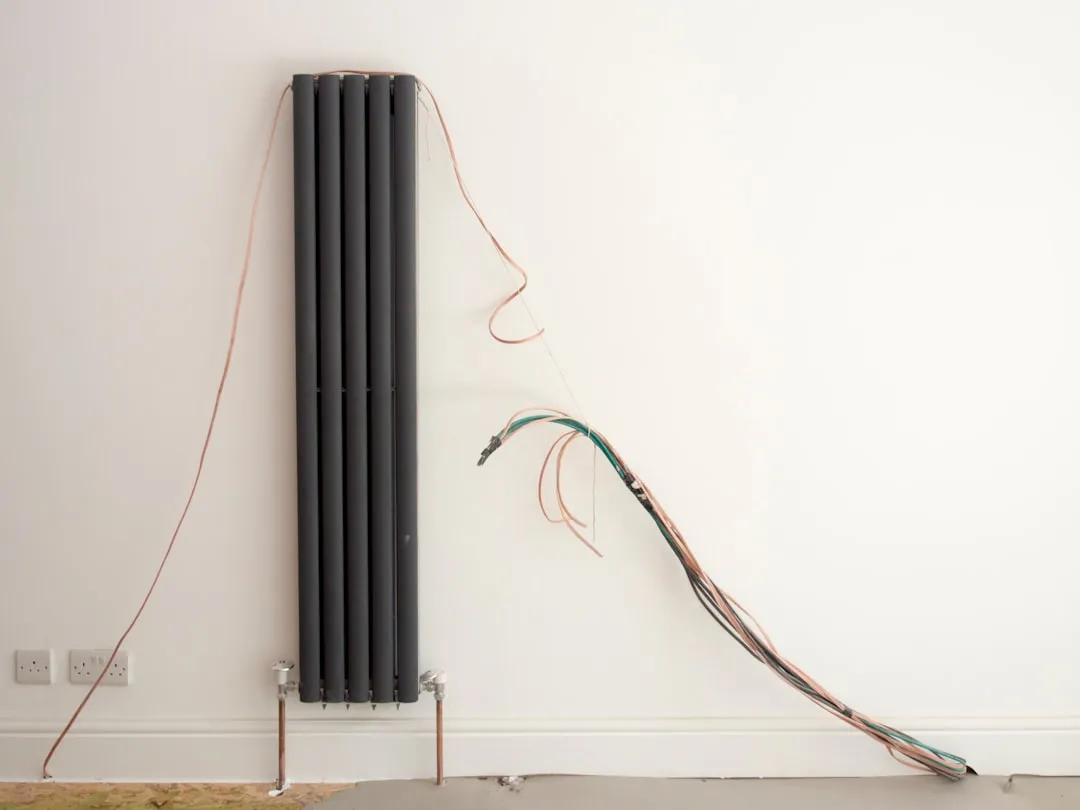 A radiator and wires on a white wall