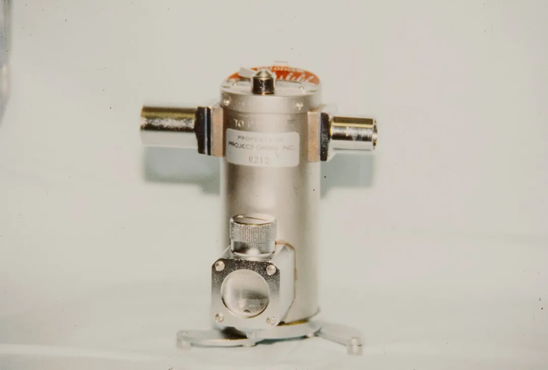 A metallic cylindrical object with two side connectors.
